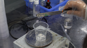 Clear adhesive poured from glass beaker in stringy stream