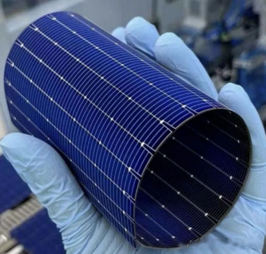 Gloved hand holding curved blue flexible solar cell wafer